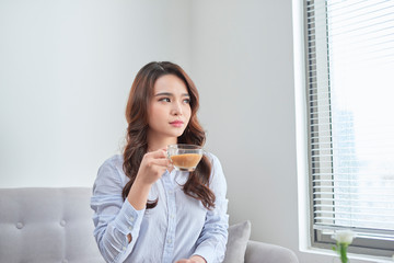 Cheerful woman relaxing in sofa and drinking tea