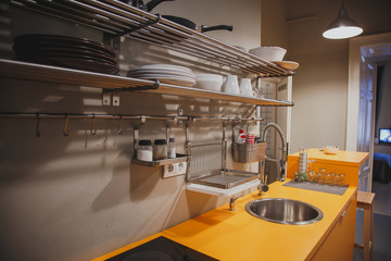 Modern kitchen interior, orange worktop, sink, stove, open shelving with dishes 1