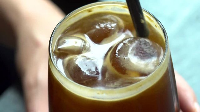 stirring iced coffee close up