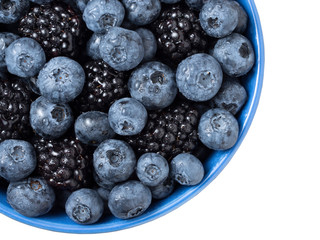 Forest berries (blueberry,bramble) in a ceramic blue  bowl. Top view.