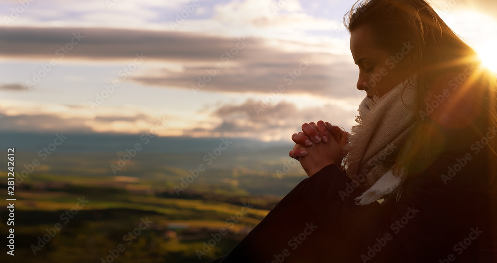 Wall mural christian worship and praise. a young woman is praying and worshiping in the evening.