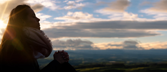 Christian worship and praise. A young woman is praying and worshiping in the evening.