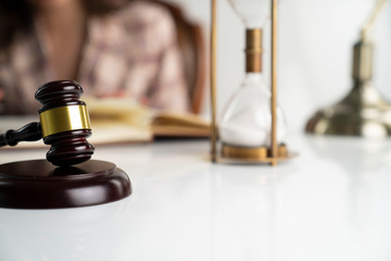 Female attorney in the legal office. Gavel, legal code and hourglass on the white table.
