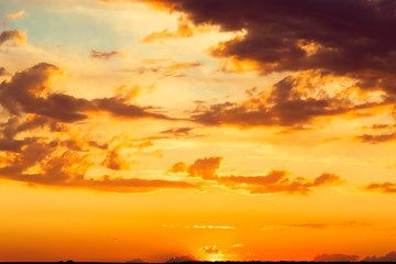 Beautiful bright majestic dramatic evening sky at sunset orange color with rays. The sun shines over the horizon against the backdrop of thunderclouds at dusk