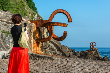 Fototapeta premium Woman taking photos at the Comb of the Wind in Donostia-San Sebastian, Spain