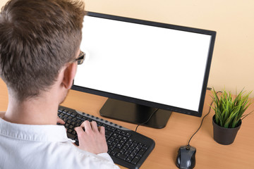 Businessman looking at computer screen using a desktop computer with a view over his shoulder from...