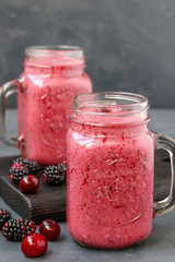 Smoothies with blackberries and cherries in glass on a dark background, vertical orientation