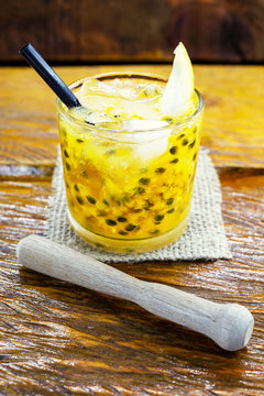 Caipirinha drink, made of cachaça and passion fruit. Traditional alcoholic drink from Brazil wood background. Image with space for text.