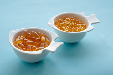fish oil capsules in a white dish on a blue background