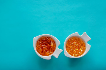 fish oil capsules in a white dish on a blue background