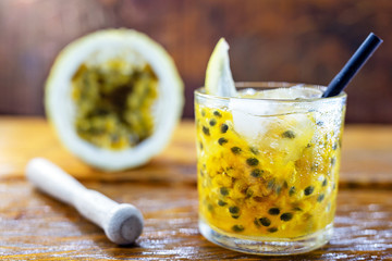 Caipirinha drink, made of cachaça and passion fruit. Traditional alcoholic drink from Brazil wood background. Image with space for text.