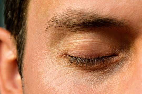 Detail of an closed eye of a handsome man. Front view. Details of a male face, closeup. 