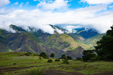 Mountain landscape beautiful green mountains with Alpine lush meadows cloudy sky background.