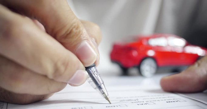 Man signing car insurance document. Writing signature on contract or agreement. Buying or selling new or used vehicle.