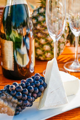 Grapes and Brie cheese with sparkling wine bottle in background