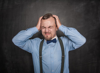 Handsome teacher man with headache on blackboard