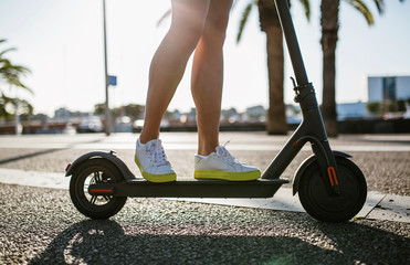 Young beautiful woman in a pink suit riding an electric scooter in the port of the sea,  modern girl, new generation, electric transport, ecology, ecological transport, dawn, electric skateboard © Chiheisen