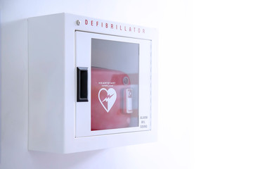 Automated External Defibrillator (AED) in white box on the wall Is an emergency pacemaker device for people with cardiac arrest. Heart defibrillator on white background. - obrazy, fototapety, plakaty