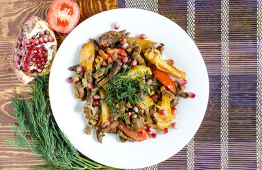 Baked veal with tomatoes decorated with greens and pomegranate fruits multicolor background