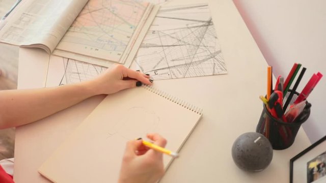 Close up woman draws a pencil on paper at home. Female fashion designer drawing sketches the dress. Fashion designer drawing and paint. Stylish loft studio. Study design tutorial animator illustrator
