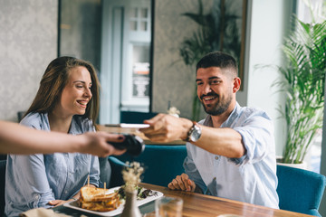 man paying the bill in restaurant contactless with his cellphone