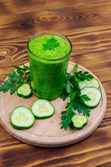 Glass of green detox smoothie of cucumber and parsley on a wooden table