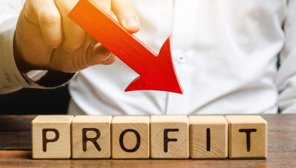 Businessman holds down arrow over word Profit. The concept of low profits in the company....