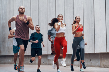Fototapeta premium Group of young people in sports clothing jogging while exercising outdoors