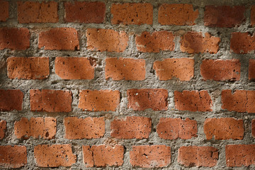 The falling rays of the sun on the old red brick wall. Texture of a rough weathered brick wall