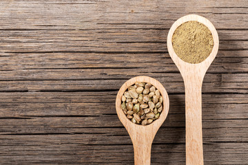 Two wooden spoons with cannabis seeds and flour on old  wooden board. Copy-space.