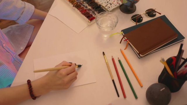 Close up shot of artist's painting in watercolors using a paintbrush on watercolors paper. Study design tutorial animator illustrator work freelance session art fashion