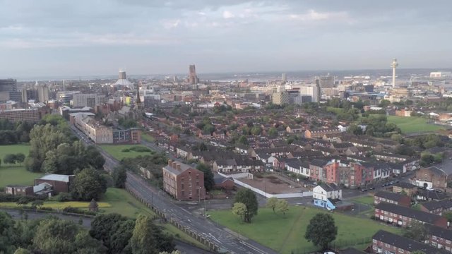 Aerial cityscape across Liverpool city buildings, cathedral, radio city tower along skyline. Descending pull back.