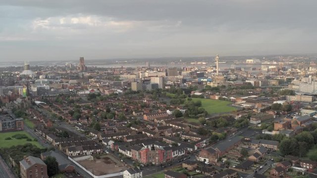 Aerial cityscape across Liverpool city buildings, cathedral, radio city tower along skyline. Ascending slow dolly left.