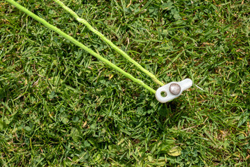Tent peg securing a green guide rope in the grass.