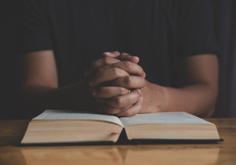 Man studying the Holy Bible on a wooden table.
