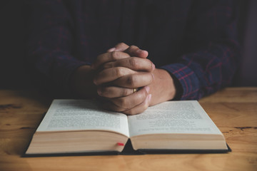 Man studying the Holy Bible on a wooden table.