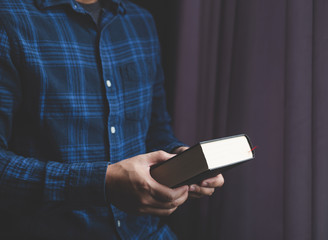 Man is holding and hug the bible in the morning. Hands folded in prayer on a Holy Bible in life concept. worship and religion. copy space