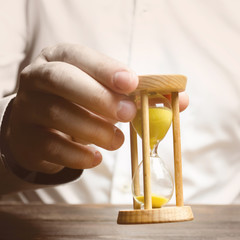 The person holds an hourglass in his hands. Business management. Logistics, process efficiency,...