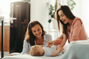 Two happy women having fun with their baby at home. - obrazy, fototapety, plakaty