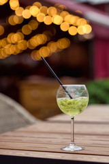 Close-up glass with green summer cocktail and beautiful bokeh