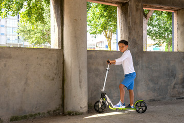 Boy playing on his scooter inside an abandoned building in the local park 