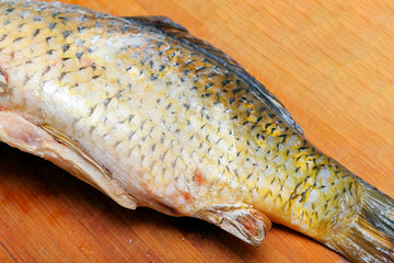Thawed freshwater fish on a wooden board.