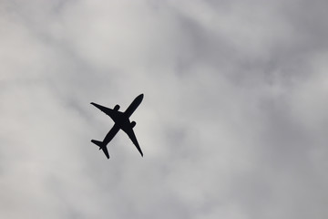 Airplane silhouette in the cloudy sky. Commercial plane taking off on background of storm clouds, turbulence concept