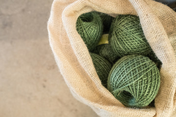 Giant balls of green string in a linen bag.