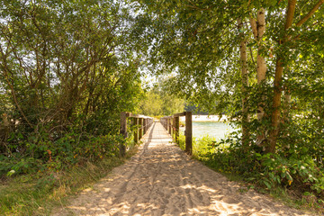 an old wooden bridge in the sand and trees around it