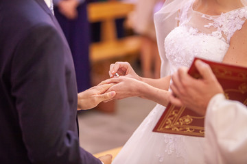Mariés qui se passent la bague au doigt durant la cérémonie de mariage