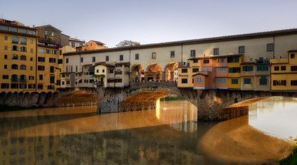 Fototapeta na wymiar Ponte Vecchio, Florence, Italy on sunset hour, golden river reflect.