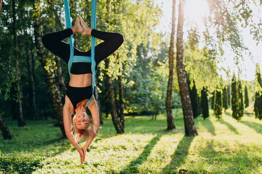 Girl practicing fly yoga at the tree hang upside down. Image