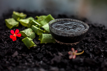 Aloe vera gel hair mask in a glass bowl consisting of activated charcoal & some aloe vera gel. To detoxify and deodorize your hair, On the wooden surface in dark colors.