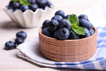 Ripe Fresh Blueberries in wooden bowl on wooden background.